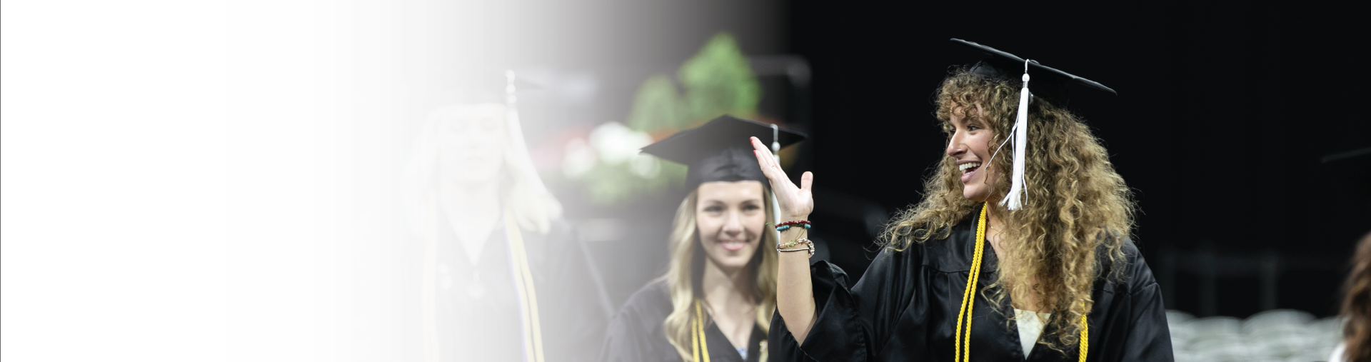 Graduate waving during commencement ceremony.