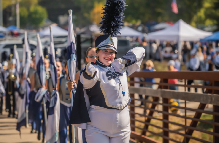 St. Ambrose marching band member leads the band across a bridge during the Homecoming parade.