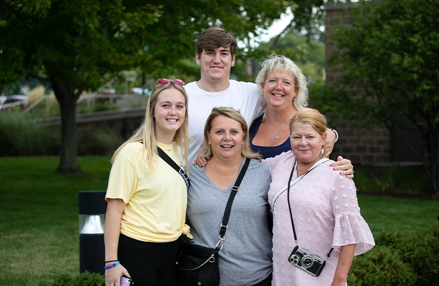 A family of five people poses outside for a group photo.