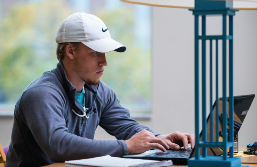 Student sitting in the library working on a laptop