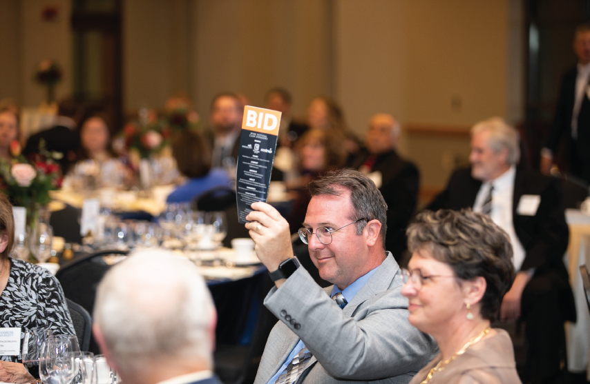 Ken Novak holding a bid sign at preview dinner for the live auction