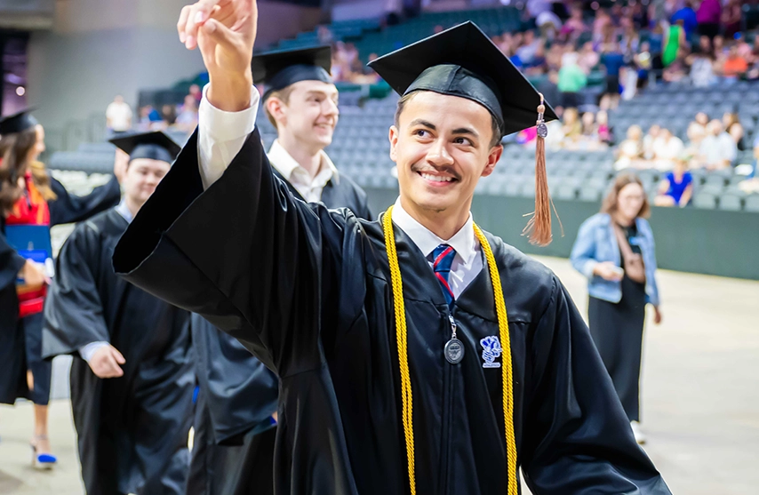 A recent graduate greets the crowd at St. Ambrose University's commencement ceremony.