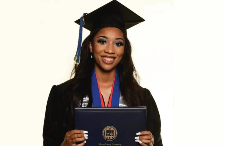 A smiling women holding a diploma from Mount Mercy University.