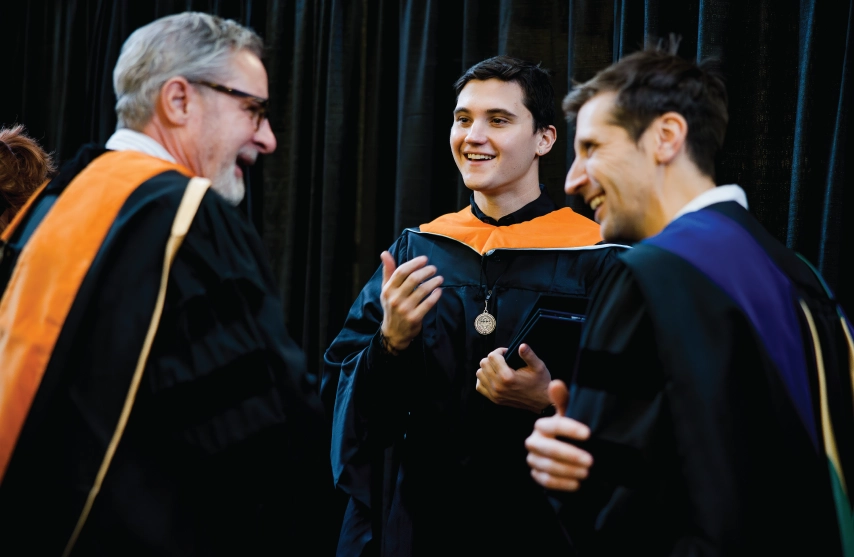 Three people smiling in a candid commencement picture.