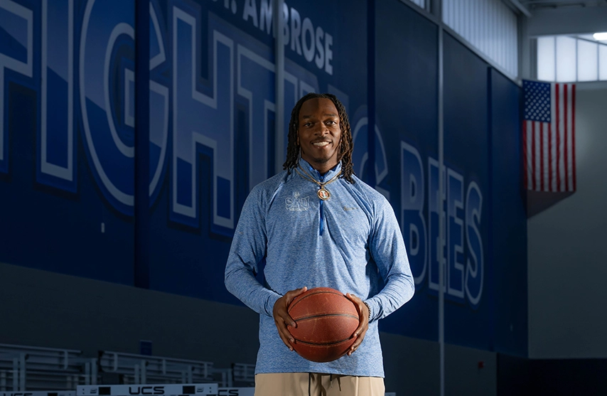 Jaylen Brazzle standing in a gymnasium holding a basketball.