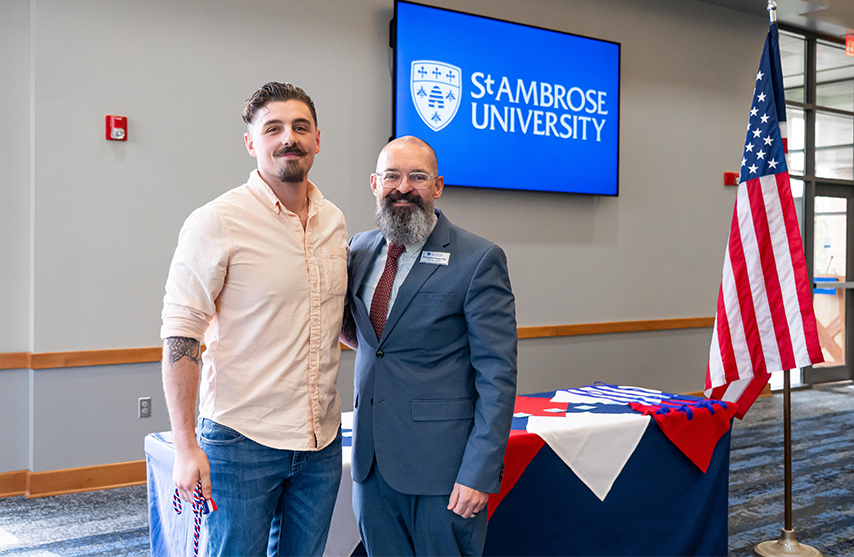 Mike Thorson stands next to the Dean of Students during the Veteran's ceremony.
