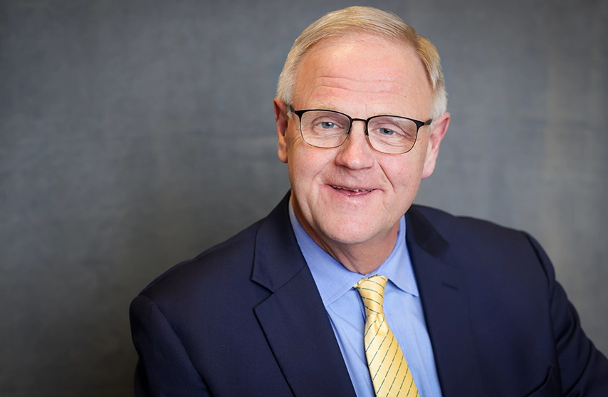 Todd Olson, PhD, smiles into the camera against a grey background.