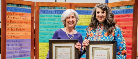 Two women holding up awards and smiling.