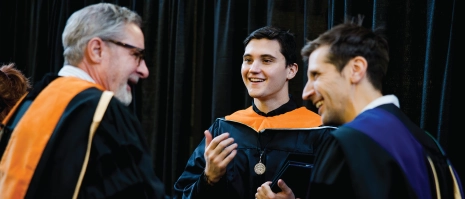 Three people smiling in a candid commencement picture.