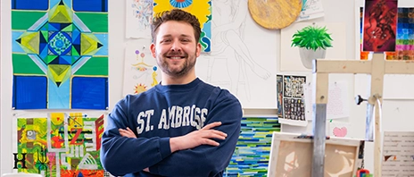 Calvin Hertel stands among canvasses, paints, and other art materials in an art studio at St. Ambrose University.
