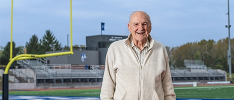 Donor Ivan Schrodt poses outside in front of the Jack and Pat Bush Stadium, home of the St. Ambrose Fighting Bees.