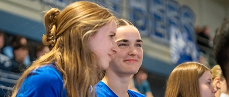 Students sit together and smile at St. Ambrose University.