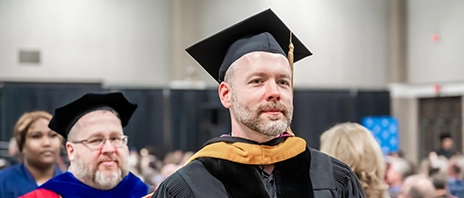 Professors in full commencement regalia walk to the stage.