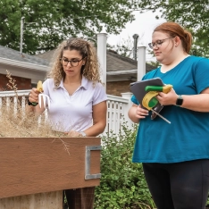 Two women working conducting an assessment outdoors next to a raised planter.