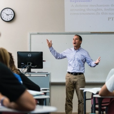 A man teaching in a classroom filled with attentive students.