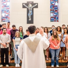 A priest leading a group of students.