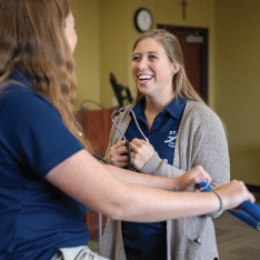 A woman conducting an evaluation on another woman during a physical therapy training.