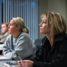 A woman looking attentively ahead in a classroom.