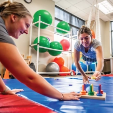 Two students participating in a sensory and motor skills assessment in an occupational therapy classroom.