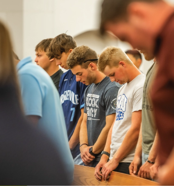 Three students praying during chapel service.