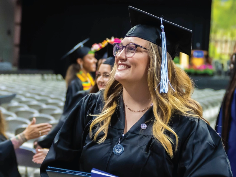 Bachelor student smiling during commencement ceremony.