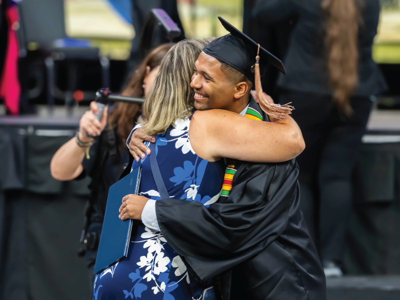 Graduate hugging staff person at commencement.