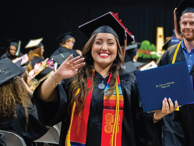 Graduate waving during commencement ceremony.