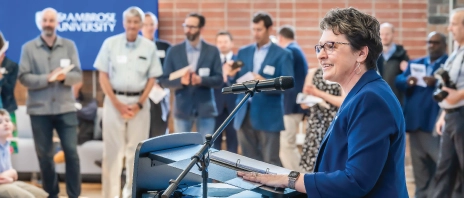 Dr. Amy Novak speaking in front of a crowd in the new Higgins Hall