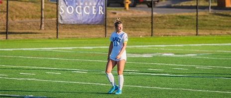 A SAU student athlete stands on the soccer pitch and looks over her shoulder.