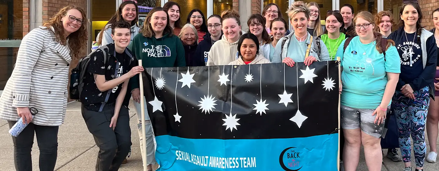 A group of students posing with a Take Back the Night banner