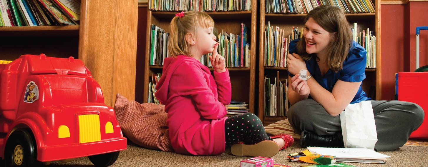 Speech language therapist conducting assessment with child in a playroom.