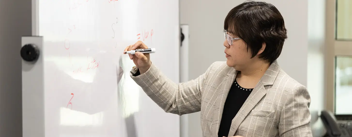 A woman writing on a whiteboard, illustrating her ideas and thoughts.