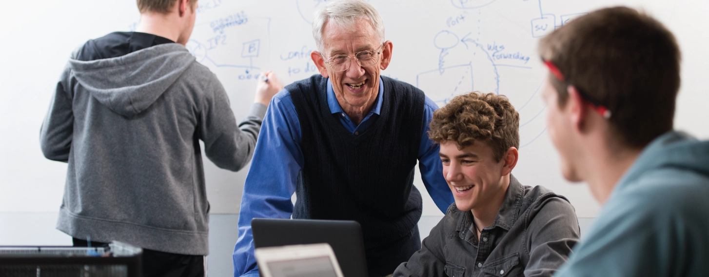 Computer science professor in classroom helping students.