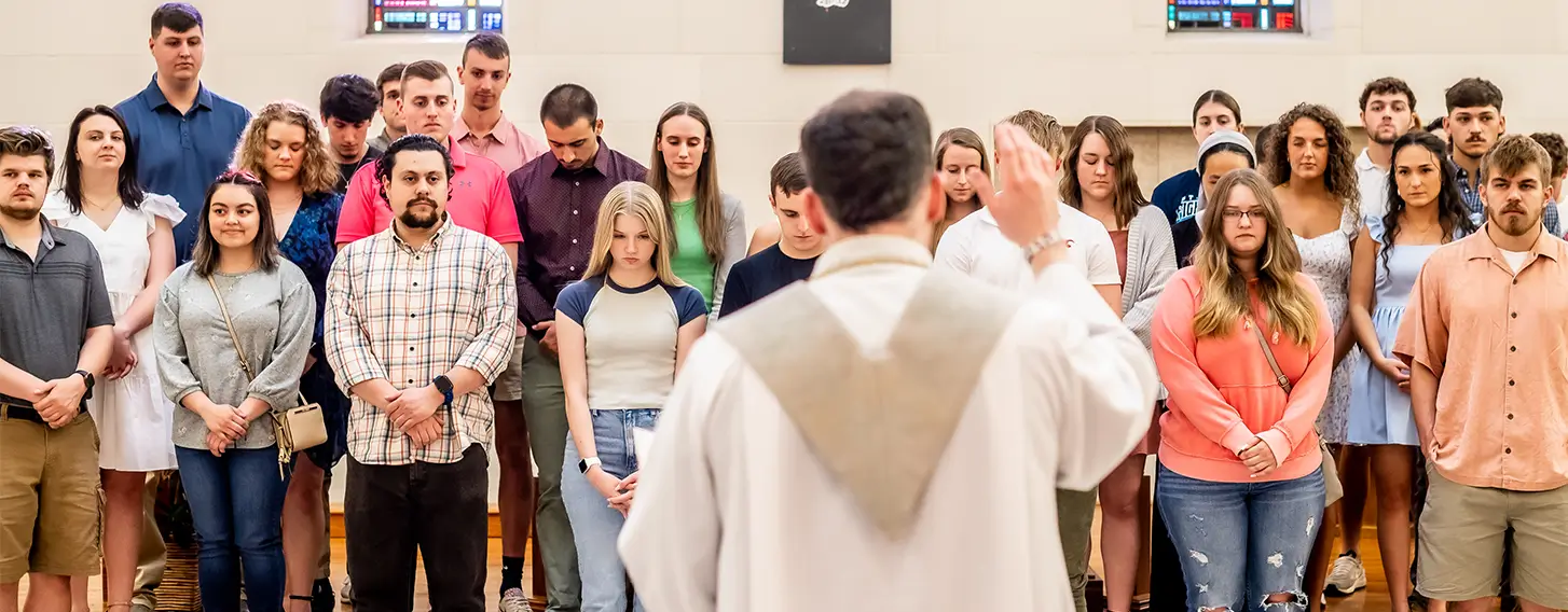 A priest leading a group of students.