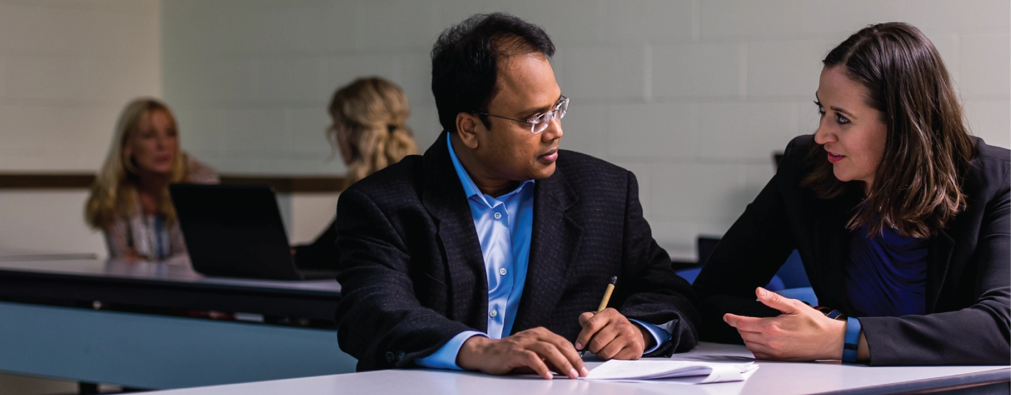 DBA student and professor talking over notes in a classroom.