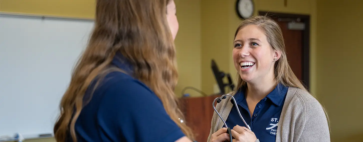 A woman conducting an evaluation on another woman during a physical therapy training.