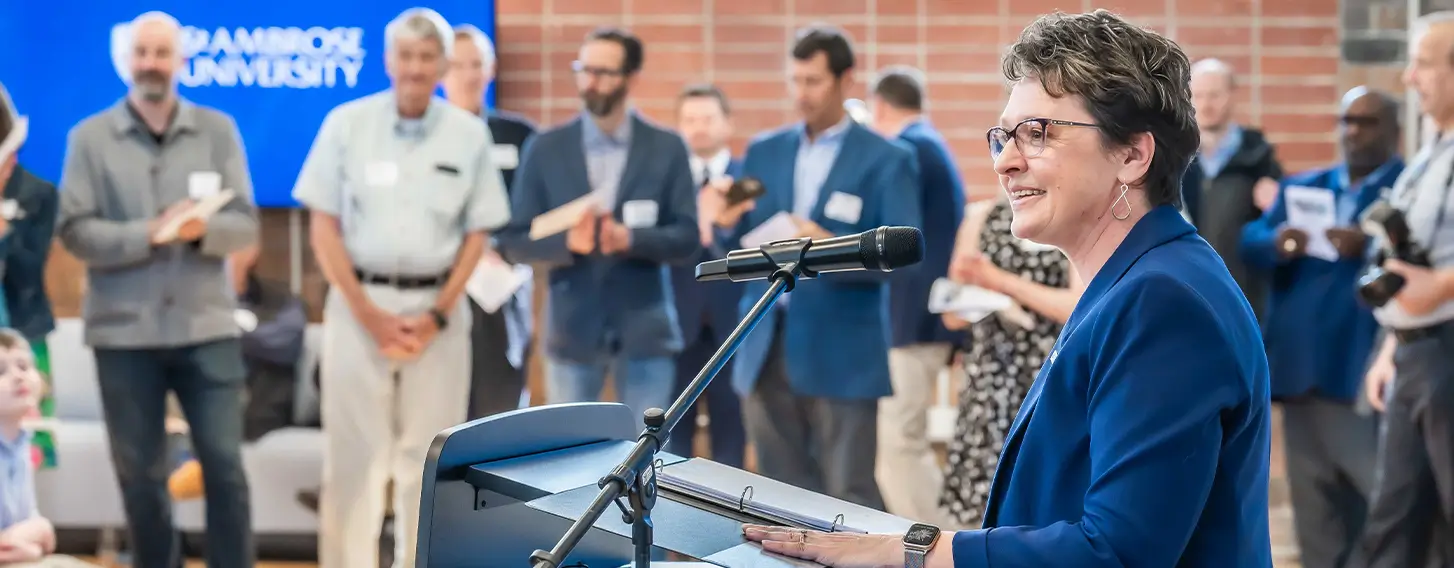 Dr. Amy Novak speaking in front of a crowd in the new Higgins Hall