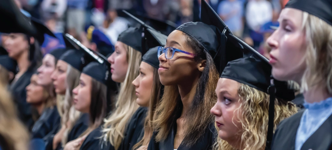 Graduates in a row looking upward during commencement ceremony.