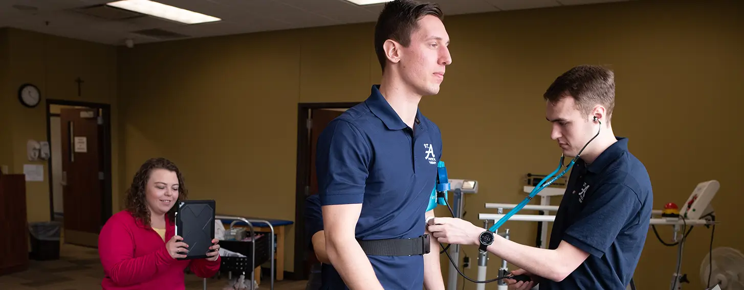 A man on a treadmill being monitored by students in a musculoskeletal lab.