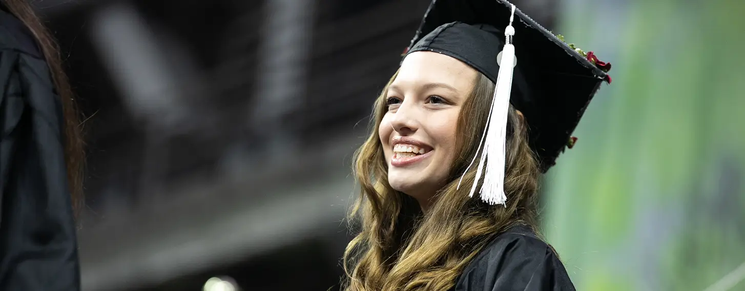 A smiling girl in a graduation gown and cap.