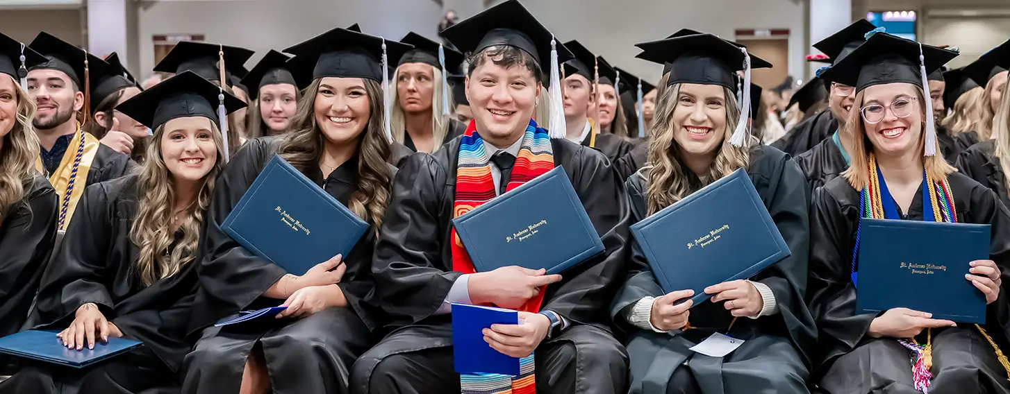 Students posing at commencement with their diploma cover