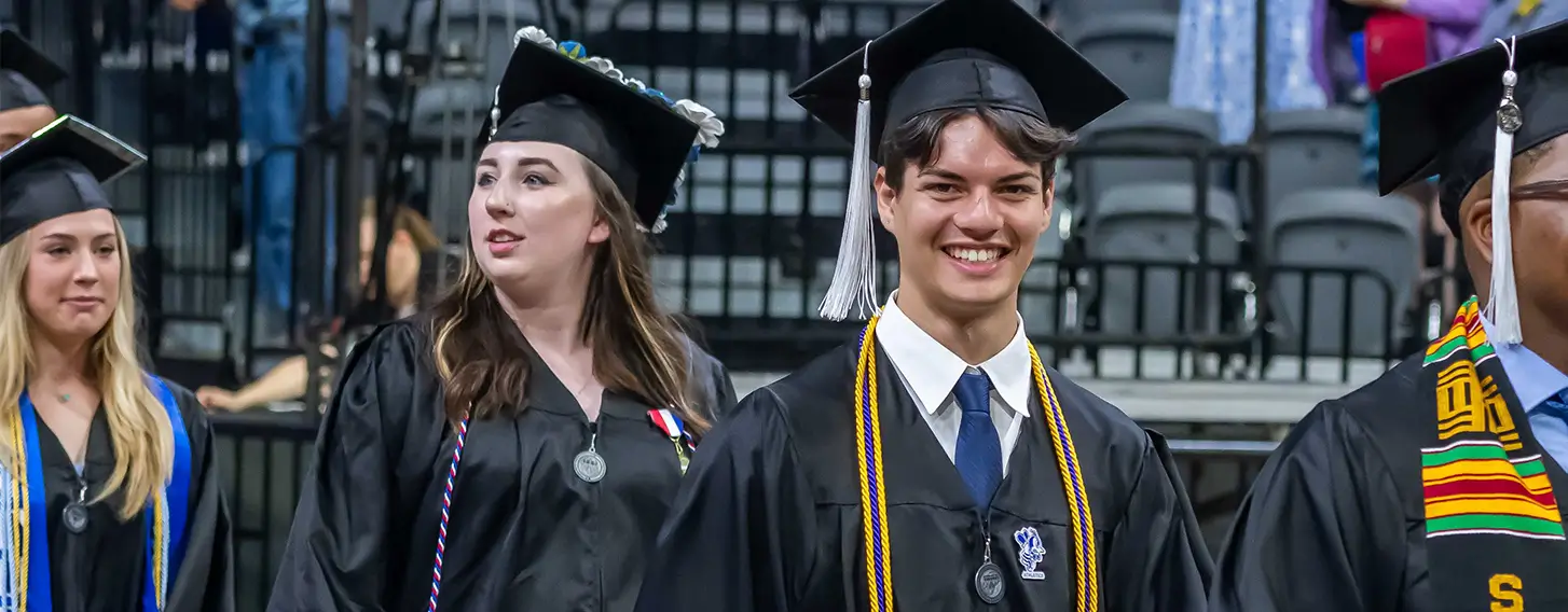 Student smiling at commencement while walking in