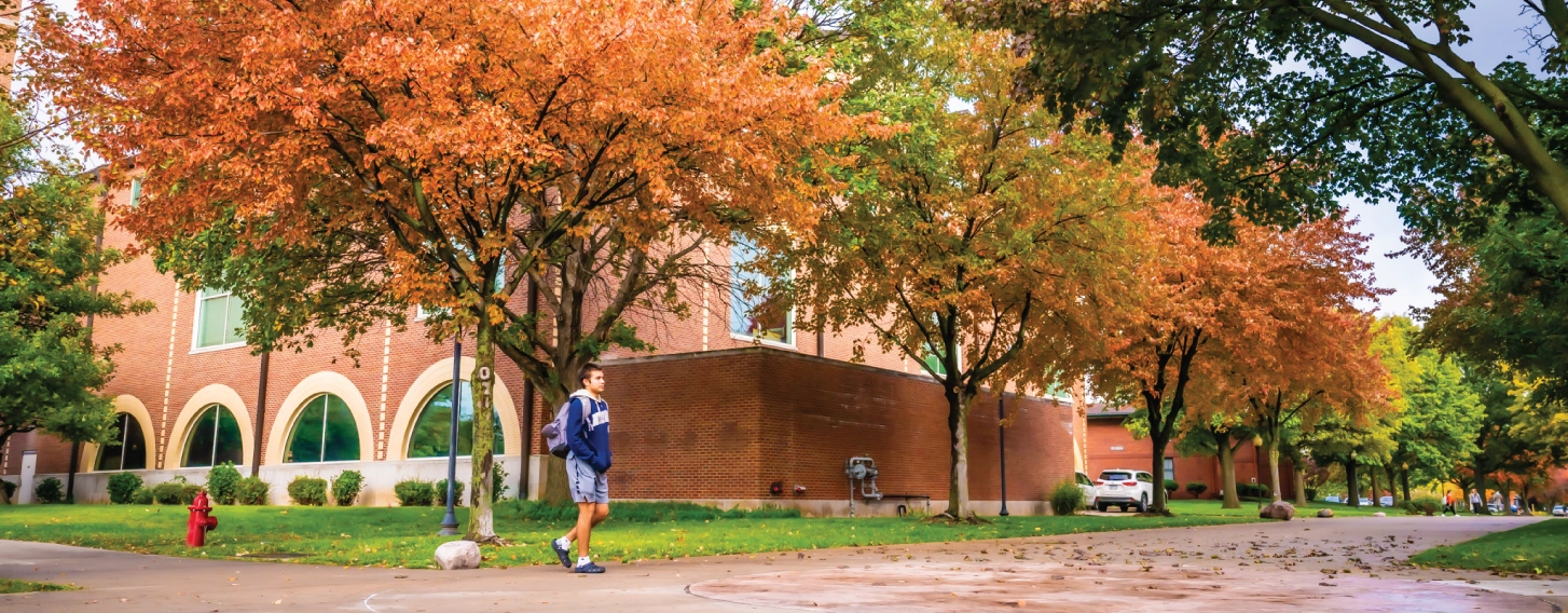 Student walking across campus in the fall.