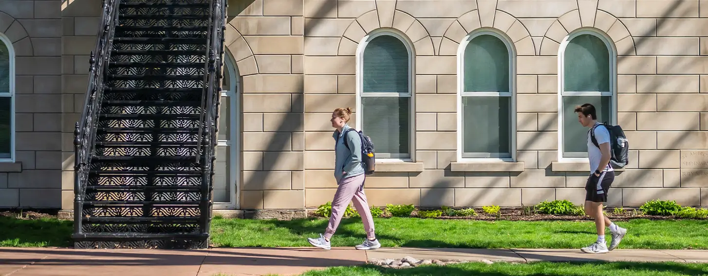 Two students walking outside of Ambrose Hall