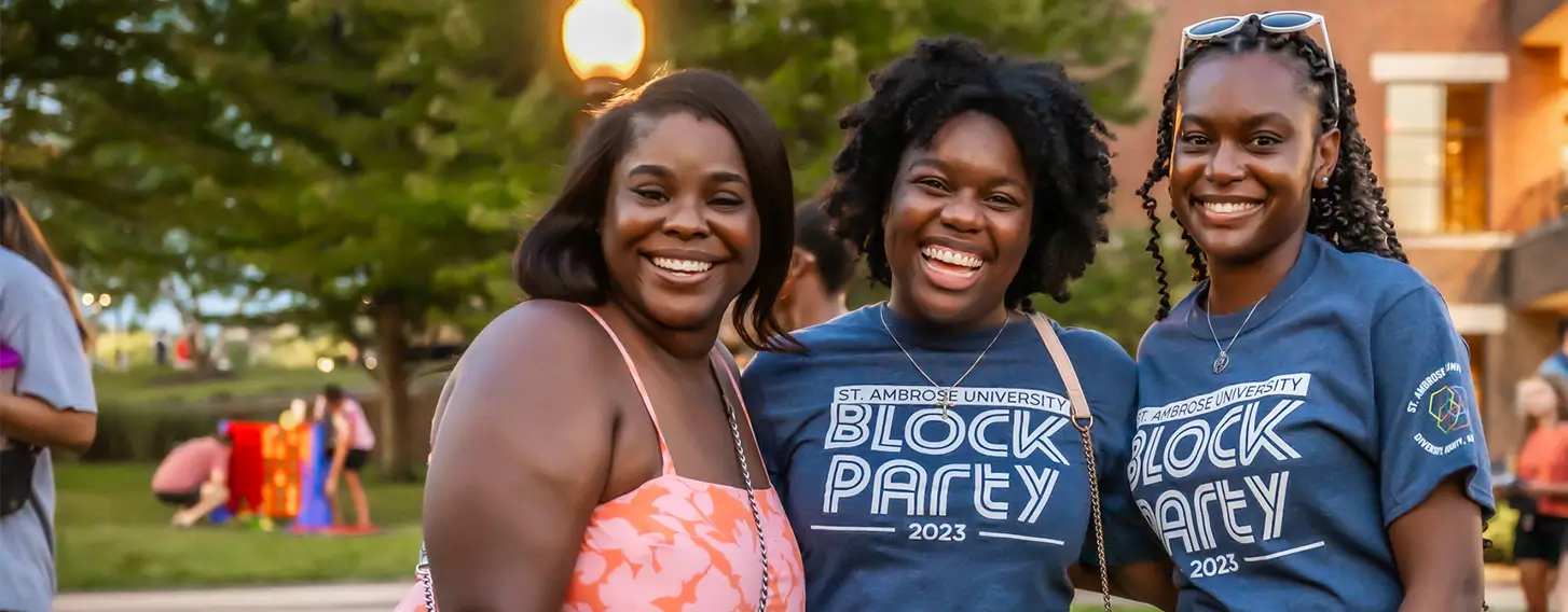 Three women smiling at a student block party.