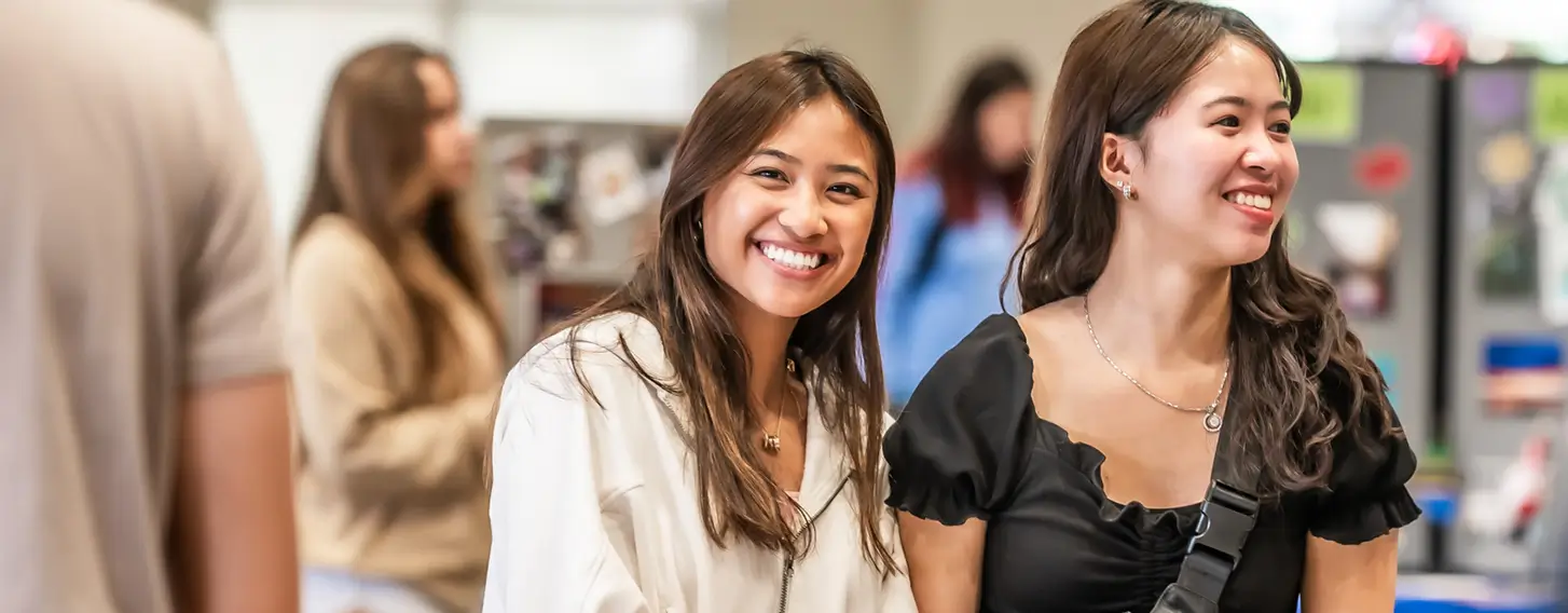 Two female students smiling at a club event