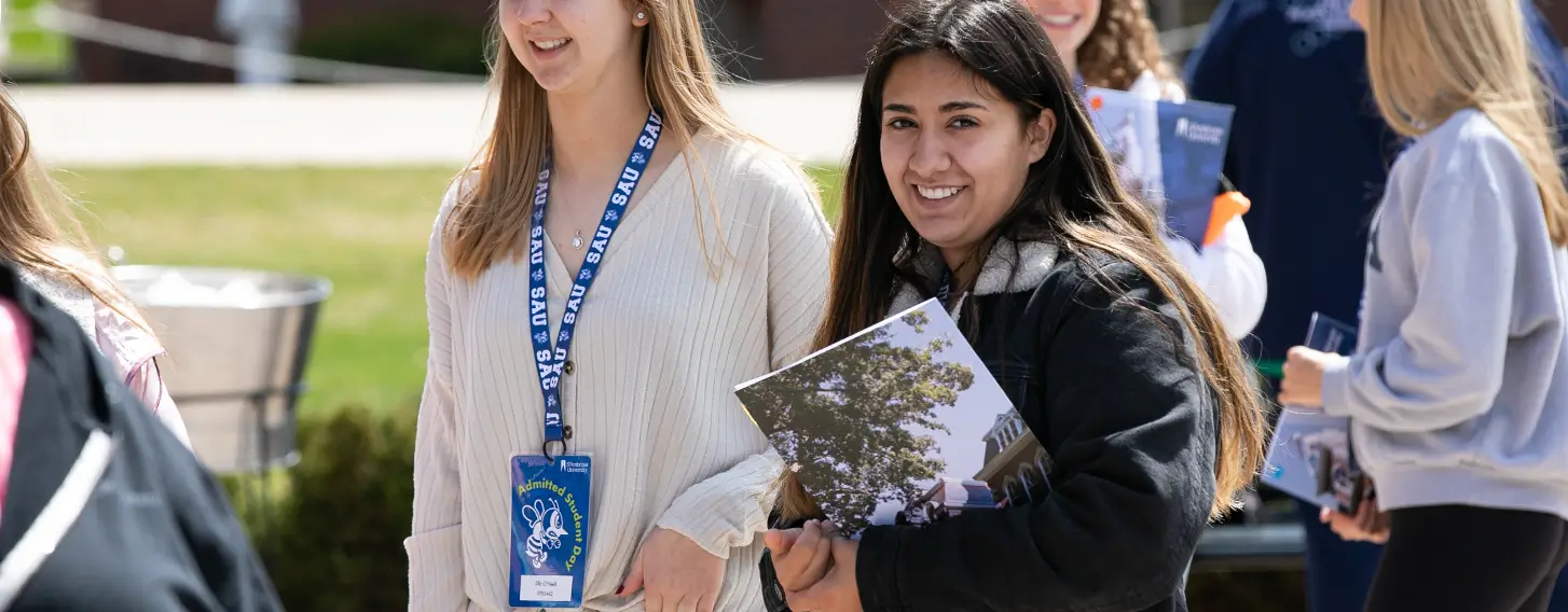 Students standing outside, holding informational brochures