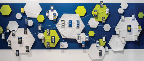 A graphic design exhibit on a blue wall featuring the UX experience for a mobile app.