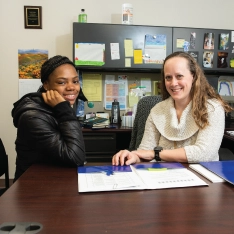 Two women sitting at a desk, looking over a folder together at Student Support.