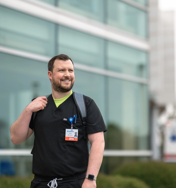 Nurse poses for a photo outside of a hospital.